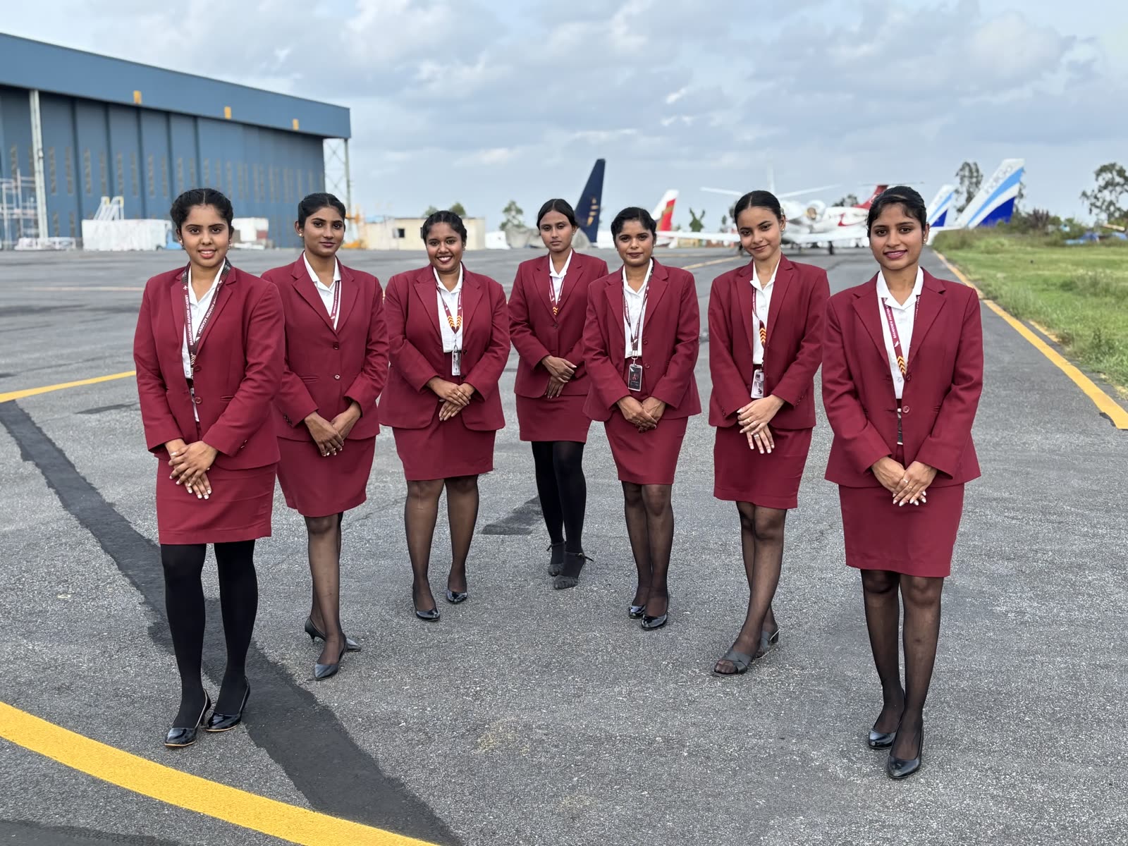 Seven trainees lined up on the apron in front of parked aircraft