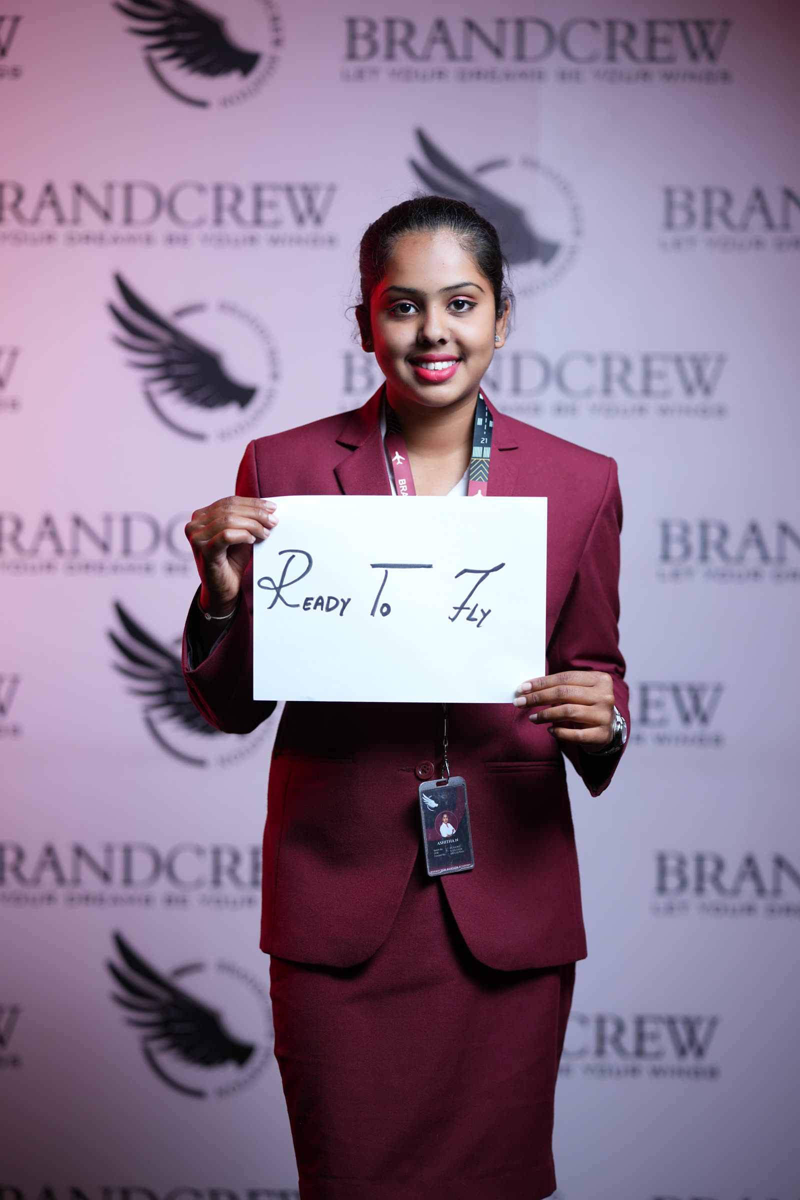 A smiling trainee holding a handwritten sign reading Ready To Fly