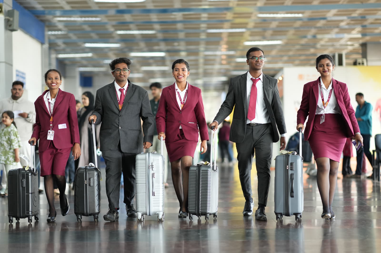 Five students with cabin bags walking through the terminal