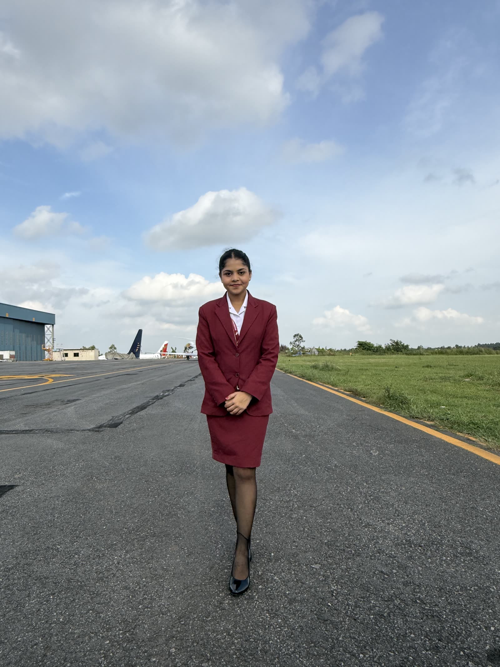A young cabin crew trainee standing on an airfield taxiway