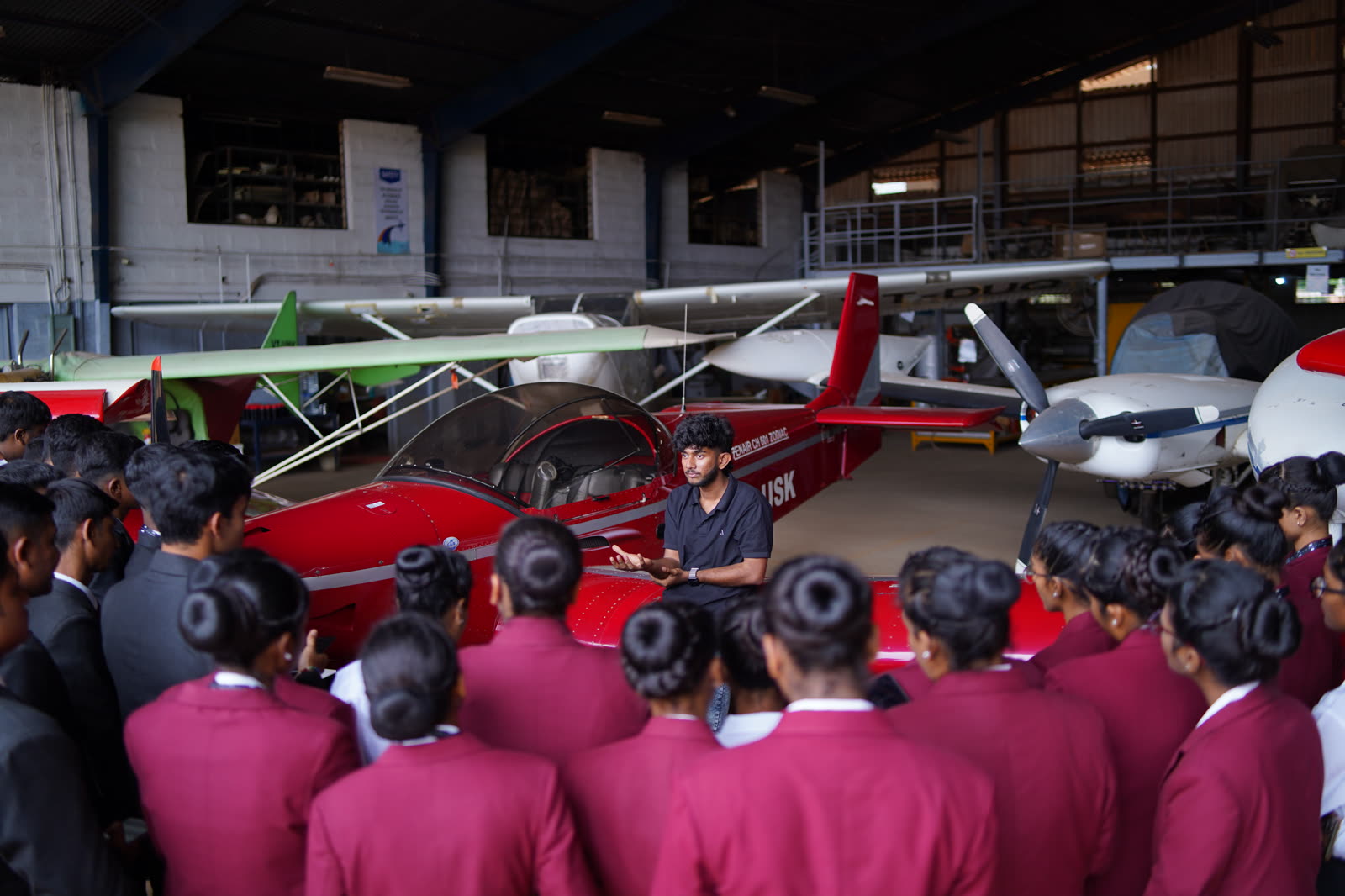 An instructor briefing students beside a trainer aircraft in the hangar