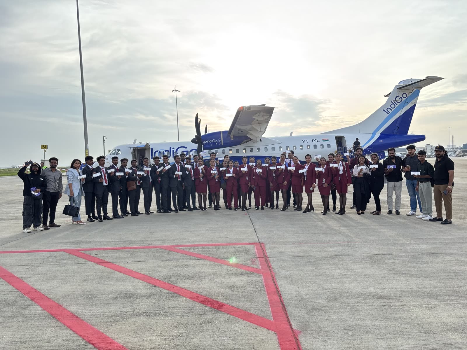 The cohort holding tickets in front of an IndiGo ATR before a training flight