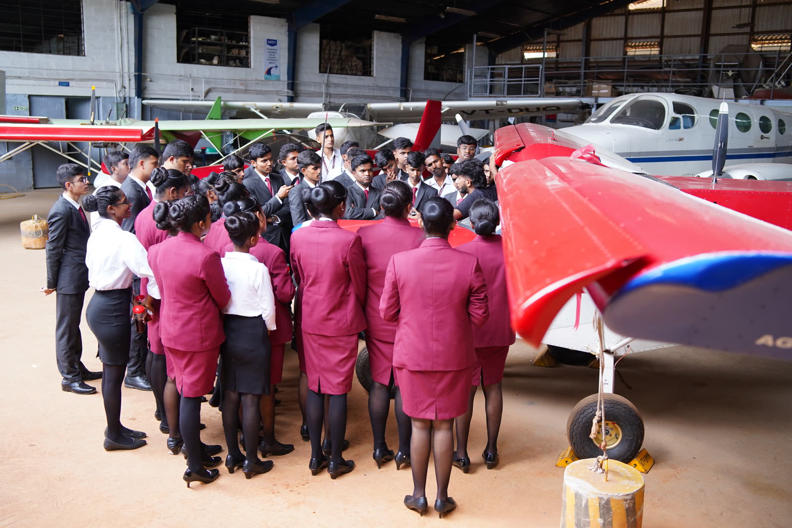 Students gathered around a trainer aircraft wing inside the hangar