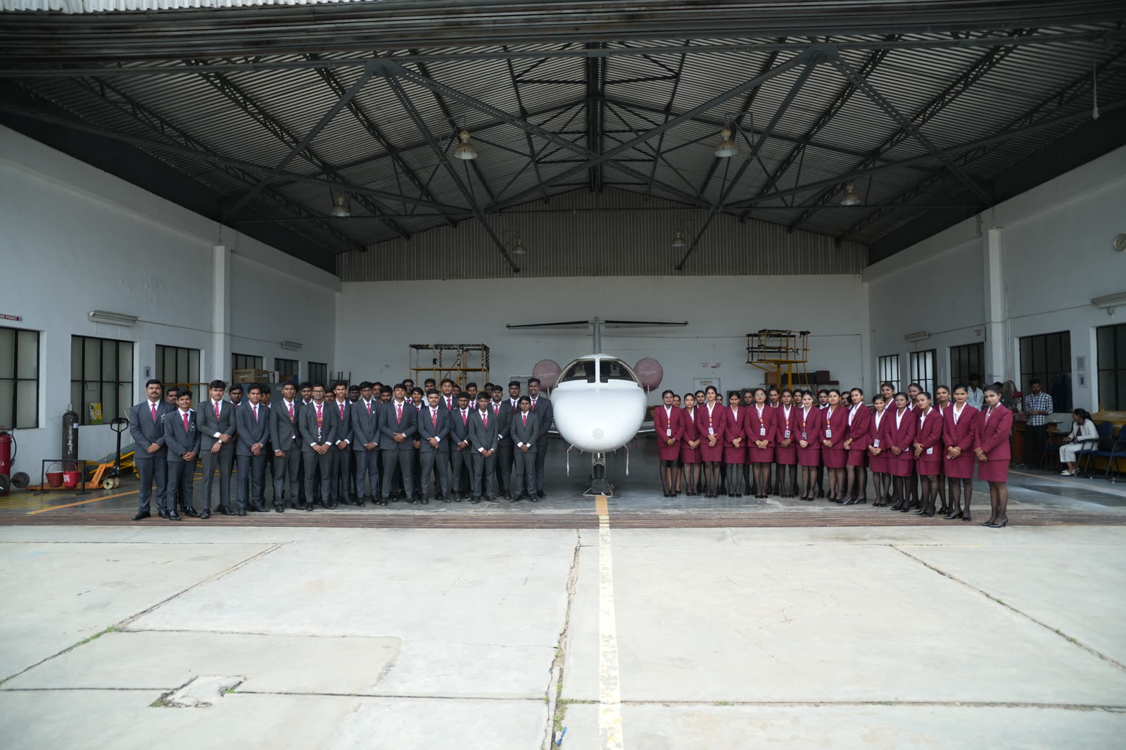 The full Brandcrew cohort lined up on both sides of an aircraft inside the hangar